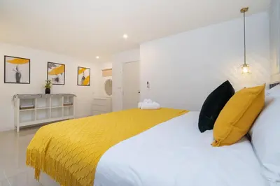 a bedroom with a large bed with a yellow blanket at Winks House Patong Phuket 4B in Patong Beach