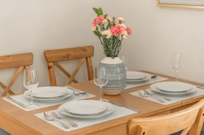 a table with plates and glasses and a vase with flowers at Title Halo 1st Floor Naiyang Pool Gym 2BR in Nai Yang Beach
