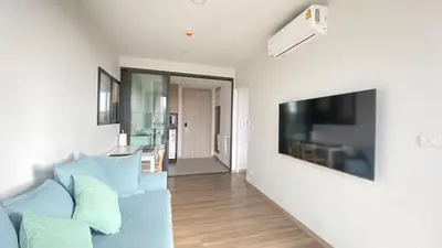 a living room with a blue couch and a flat screen tv at 1BDR Laguna 10 min to the Sea Roof Pool in Laguna Phuket