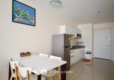 a kitchen with a white table and chairs and a refrigerator at At Sea Condotel in Klong Muang Beach