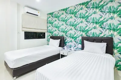 two beds in a room with a green and white wallpaper at Songbird Suites - Deluxe Twin Suite and Scooter in Ao Nang Beach