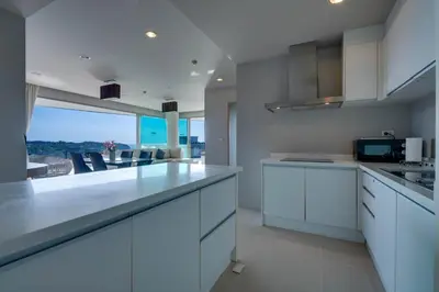 a kitchen with white cabinets and a view of the ocean at Veloche Apartment by Continent in Karon Beach
