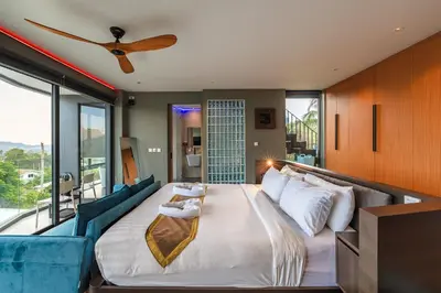 a bedroom with a large bed and a blue couch at V160 Beautiful Sea View Full Smart House 3BR in Rawai Beach