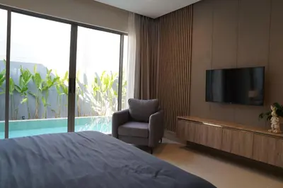 a bedroom with a bed and a tv and a chair at Zenithy Villas 3BD in Phuket
