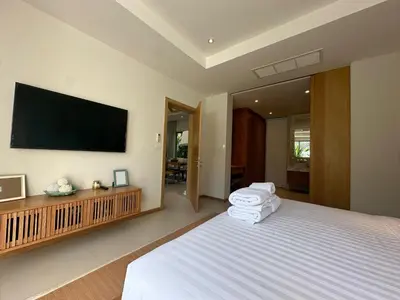 a bedroom with a large bed with a flat screen tv at Trichada Sky 3BD in Phuket