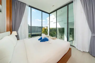 a bedroom with a white bed and large windows at Amor Primero - sea view pool villa with maid in Kamala Beach