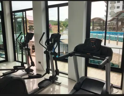 a gym with three exercise bikes and a swimming pool at Chalong Miracle Lakeview in Chalong