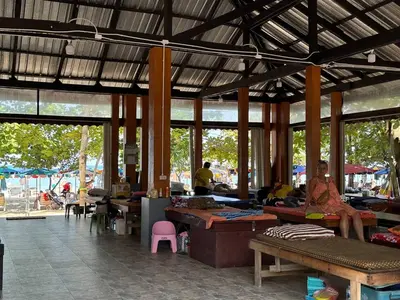 a woman sitting on a bench in a market at Title Halo Romantic Suite Pool View Gym in Nai Yang Beach
