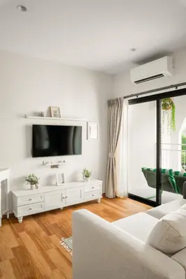 a white living room with a tv and a couch at Title Halo Romantic Suite Pool View Gym in Nai Yang Beach
