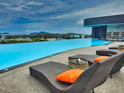 a swimming pool with two wicker chairs with orange pillows at La Vita 5 Stars Great 1 Bdr 3 Pool in Phuket Town