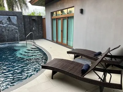 a swimming pool with two benches next to a building at Ocean Villa Bang Tao Phuket in Ban Thalat Choeng Thale