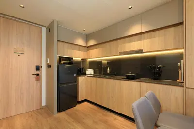 a kitchen with wooden cabinets and a stainless steel refrigerator at New 1bdr apartment BangTao Beach C410 in Laguna Phuket