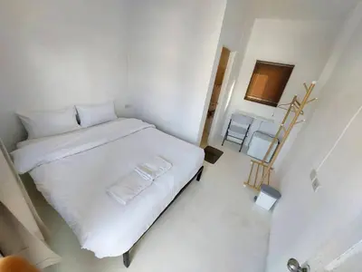 a small white bedroom with a bed and a chair at XX BAO Patong Beach Phuket II เบา ป่าตอง บีช ภูเก็ต in Patong Beach