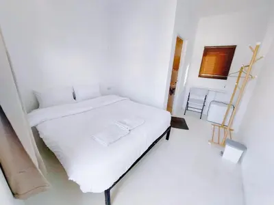 a white bedroom with a white bed and a chair at XX BAO Patong Beach Phuket II เบา ป่าตอง บีช ภูเก็ต in Patong Beach