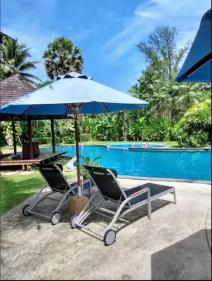two chairs and an umbrella next to a pool at casuarina shores penthouse in Bang Tao Beach