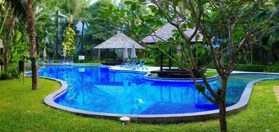 a large blue swimming pool with chairs and trees at casuarina shores penthouse in Bang Tao Beach