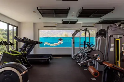 a gym with treadmills and a woman in the water at Private Pool View 1BR Apartment in Naiharn Residence near Beach, UTN D502 in Rawai Beach