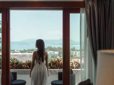 a woman in a white dress looking out of a window at Baan View Talay - Sea View Zenith Villa By Elite Havens in Surin Beach