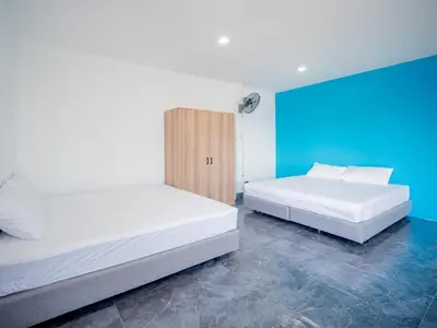 two beds in a room with a blue wall at Los Patios Hostel Phuket in Mai Khao Beach