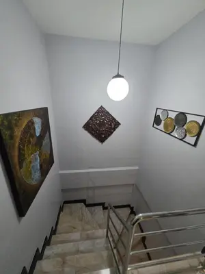 a staircase with a light fixture and paintings on the wall at Diamond Home in Phuket in Ban Rangeng