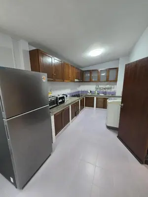 an empty kitchen with a refrigerator and wooden cabinets at Diamond Home in Phuket in Ban Rangeng