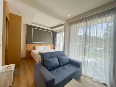 a bedroom with a bed and a couch in front of a window at Studio surin-bangtao beach in Surin Beach