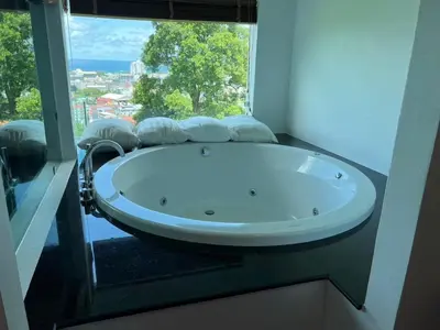 a bath tub in a room with a large window at Thebirdhouse Patong Phuket203 in Patong Beach