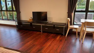 a living room with a flat screen tv on a wooden floor at Thebirdhouse Patong Phuket303 in Patong Beach