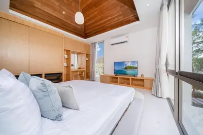 a bedroom with a large bed and a television at New Elegance & Tropical Luxury - 4BR Pool Villa in Lux Pride 2 V8 Residence, near Laguna in Bang Tao Beach