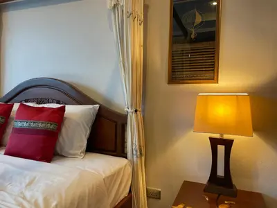 a bedroom with a bed with a lamp on a table at Вилла в сердце Пхукета in Surin Beach