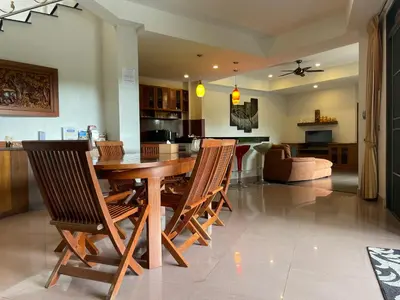 a dining room and kitchen with a wooden table and chairs at Вилла в сердце Пхукета in Surin Beach