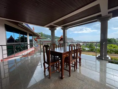 a wooden table and chairs on a balcony with a view at Вилла в сердце Пхукета in Surin Beach