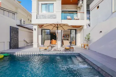 a house with a swimming pool with two chairs and an umbrella at Summer Villa Patong in Patong Beach