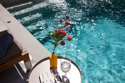 a table with a vase with flowers on it next to a pool at Summer Villa Patong in Patong Beach