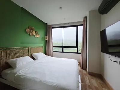 a bedroom with a white bed and a green wall at Beachside Gem with Lake, Cafes and more in Rawai Beach