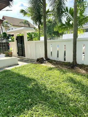 a white fence in front of a house with palm trees at Jungle Pool Villa in Chalong in Changwat Phuket