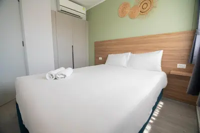 a bedroom with a large white bed with towels on it at Thai Me Up the Tower in Ban Klang