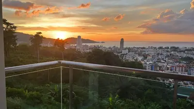 a view of a city at sunset from a balcony at Thebirdhouse Patong Phuket201 in Patong Beach