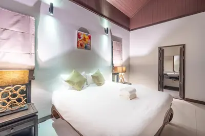 a bedroom with a large white bed and a mirror at Pasak Villa in Laguna Phuket