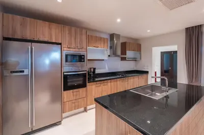 a kitchen with a stainless steel refrigerator and wooden cabinets at Pasak Villa in Laguna Phuket