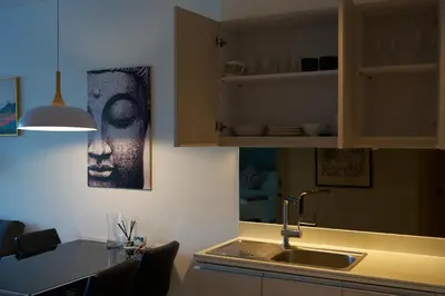a kitchen with a sink and a table with chairs at Cassia Residences 1BDR Lake view in Laguna Phuket