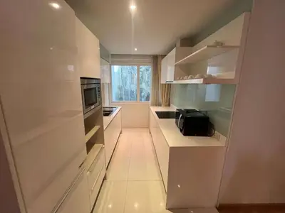 a small kitchen with white cabinets and a window at Privilège résidence patong in Patong Beach