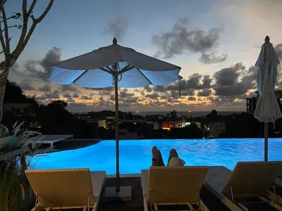 a view of a pool with an umbrella and chairs at Karon rooftop pool condo in Karon Beach