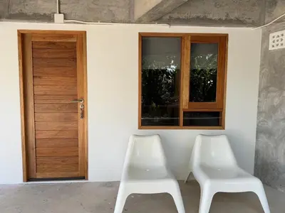 two white chairs sitting in front of a door at Cozy room Maikhao Phuket in Ban Ao Tu Khun