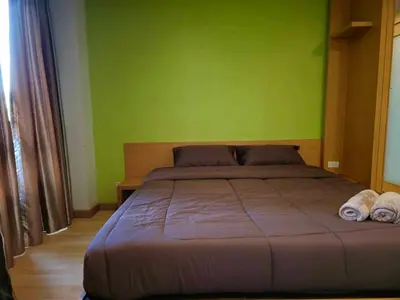 a bed in a room with a green wall at The feeltrue phuket CK in Phuket Town