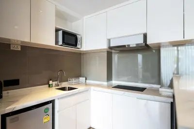 a kitchen with white cabinets and a sink and a microwave at 1Bd Сomfortable Apartment LaVita in Phuket Town
