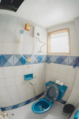 a bathroom with a blue toilet and a window at XX Mitr Inn Phuket Old Town -มิตร อินน์ ภูเก็ตโอลทาวน์ in Phuket Town