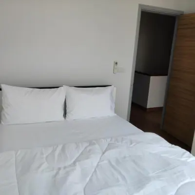 a bed with white sheets and pillows in a room at The first house 11126 in Ban Phlu Yai