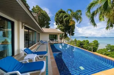 a swimming pool with blue chairs and the ocean at Pool Villa Ao Pro in Ban Ao Kung