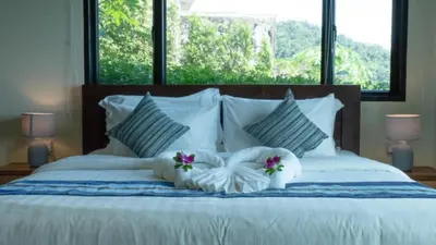 a white bed with two pillows and flowers on it at Pool Villa Ao Pro in Ban Ao Kung
